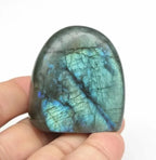 Polished labradorite freeform crystal held in hand, showing size scale and natural blue flash, approximately 5cm