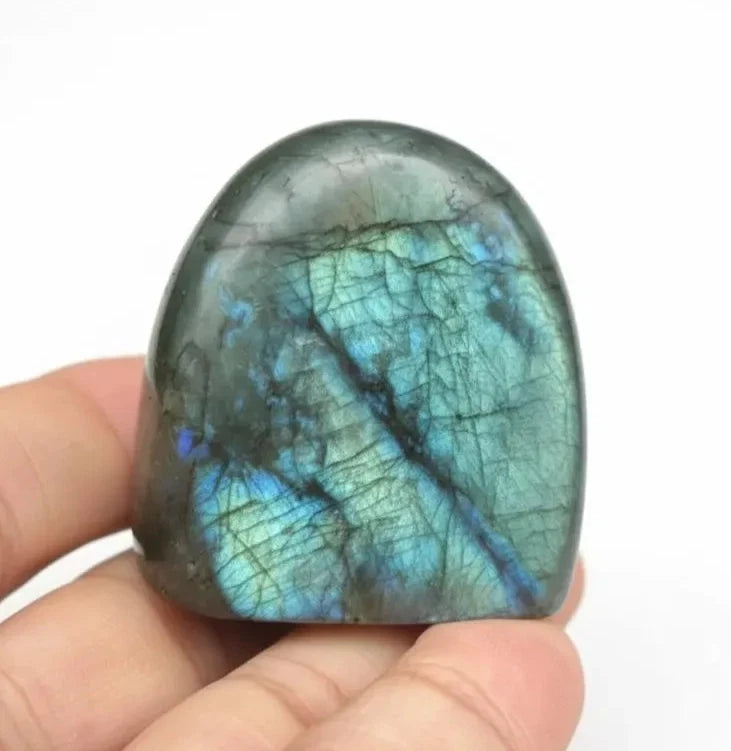 Polished labradorite freeform crystal held in hand, showing size scale and natural blue flash, approximately 5cm