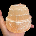 Natural red selenite candle holder displayed in hand for size reference