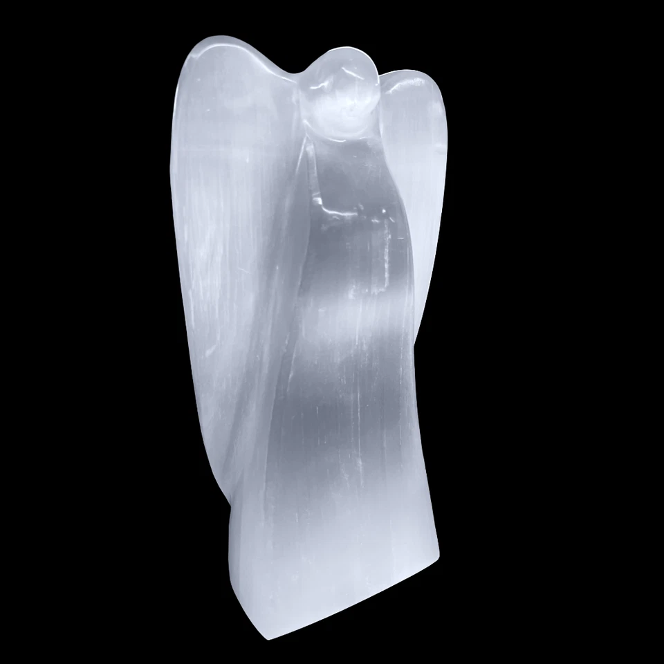 Side view of natural selenite angel lamp carving on a black background
