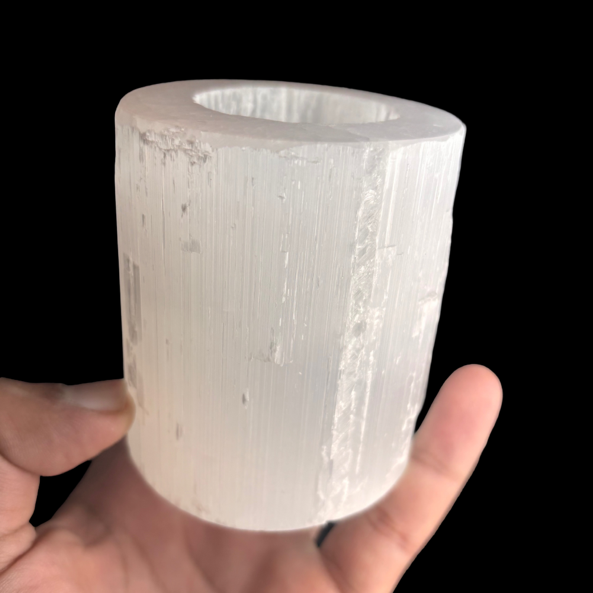 Natural selenite candle holder with polished top displayed in hand for size reference