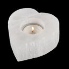 Lit tealight inside heart shaped natural selenite candle holder with polished surface and Moroccan crystal texture