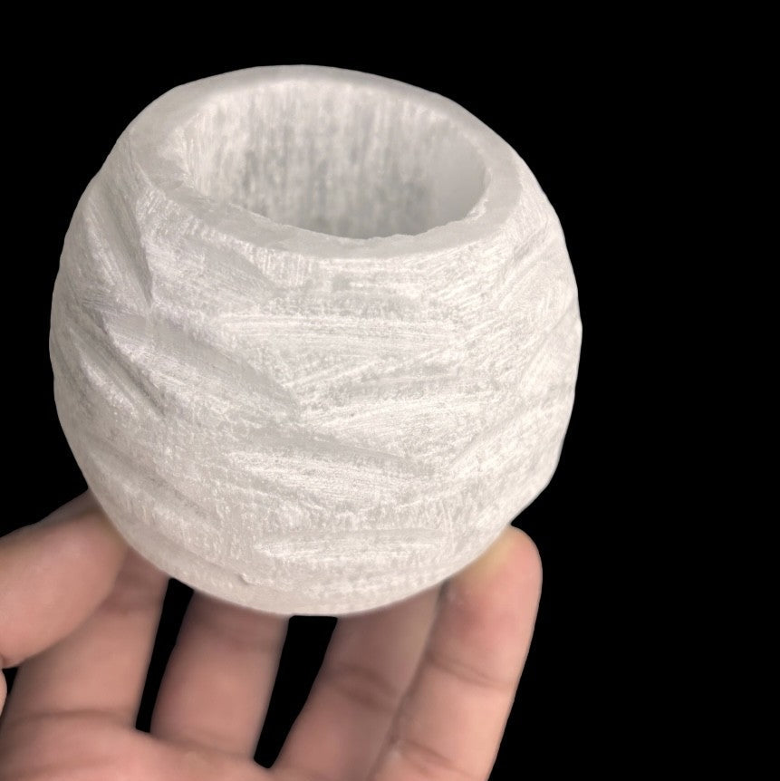 Natural selenite snowball candle holder displayed in hand for size scale